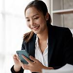 An image of a woman typing on a mobile phone in this What is mobile marketing article