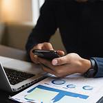 Image of business man on phone and laptop in this What Is Omnichannel Marketing In Digital Marketing article