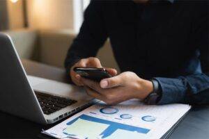 Image of business man on phone and laptop in this What Is Omnichannel Marketing In Digital Marketing article
